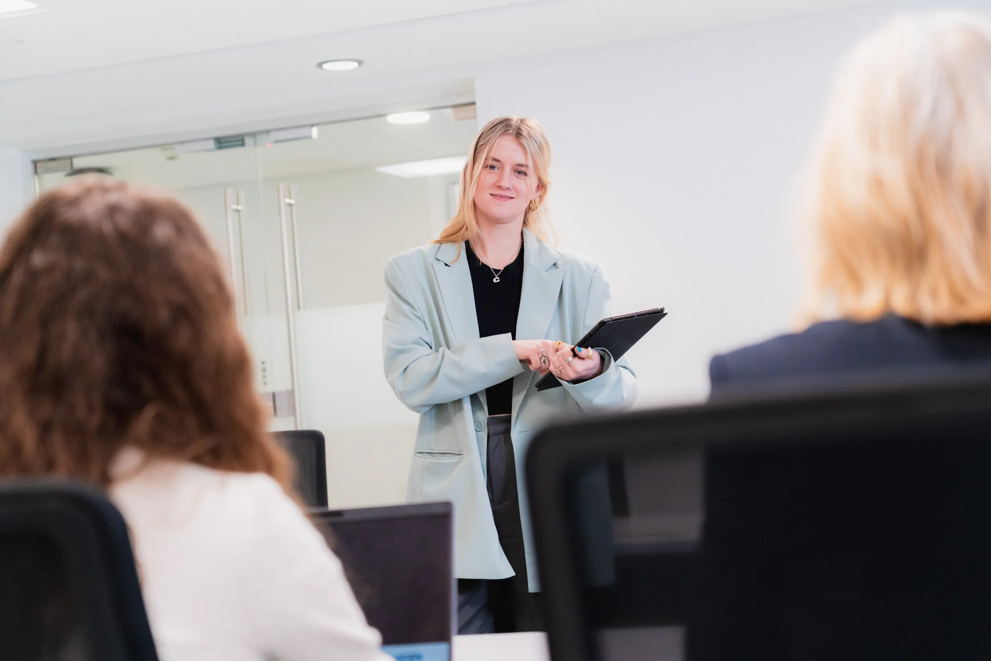 Lady holding an ipad presenting to two people