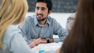 A man is involved in a group discussion in a classroom of adult learners.