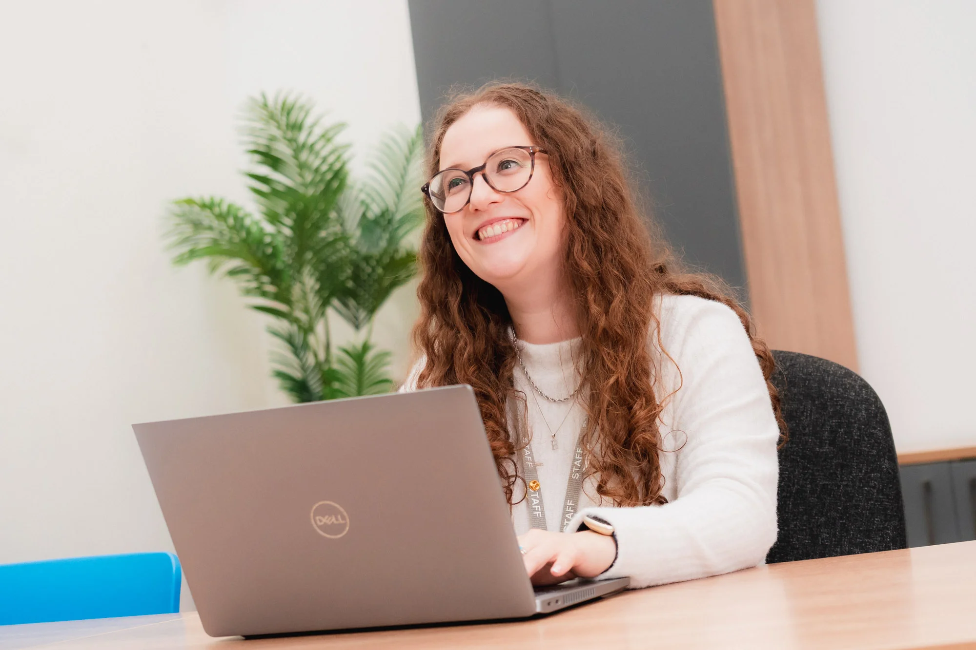 Person using a laptop in a modern office meeting room, demonstrating professional development and workplace learning through a Total People apprenticeship programme.