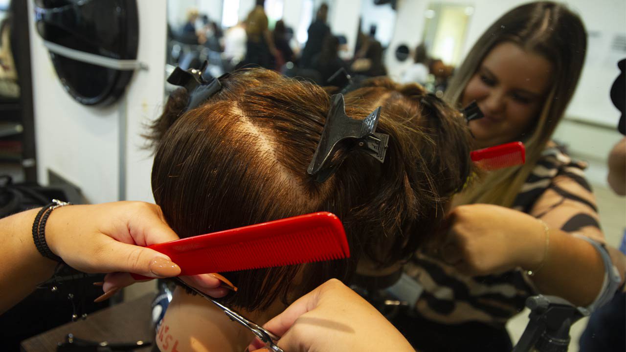 Female hair stylist cutting hair.