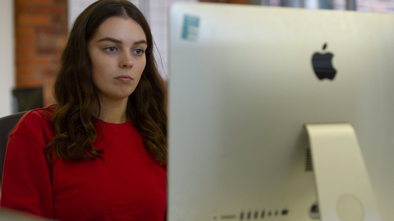 Female apprentice sat by a computer.