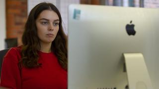 Female apprentice sat by a computer.