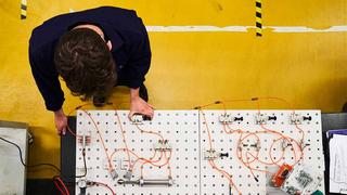 A shot from above looking directly down on an Engineering apprentice working in a workshop.