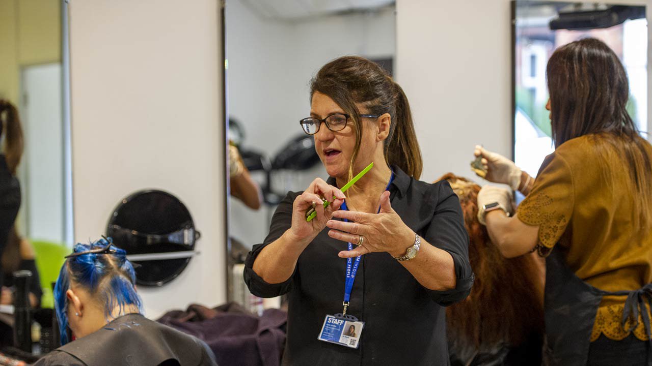 Female learning coach teaches at a hair salon.