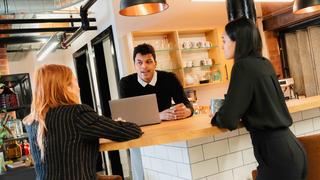 group of people talking and looking at a laptop