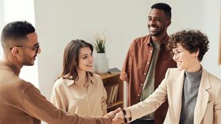 A group of people smiling and shaking hands in a professional setting