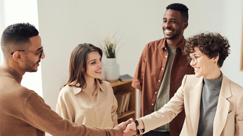 A group of people smiling and shaking hands in a professional setting