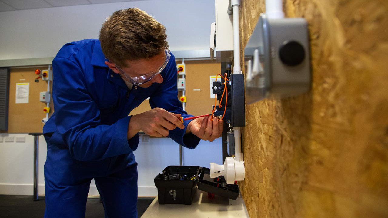 Apprentice electrician practices wiring.