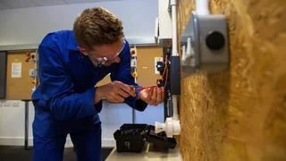 Apprentice electrician practices wiring.