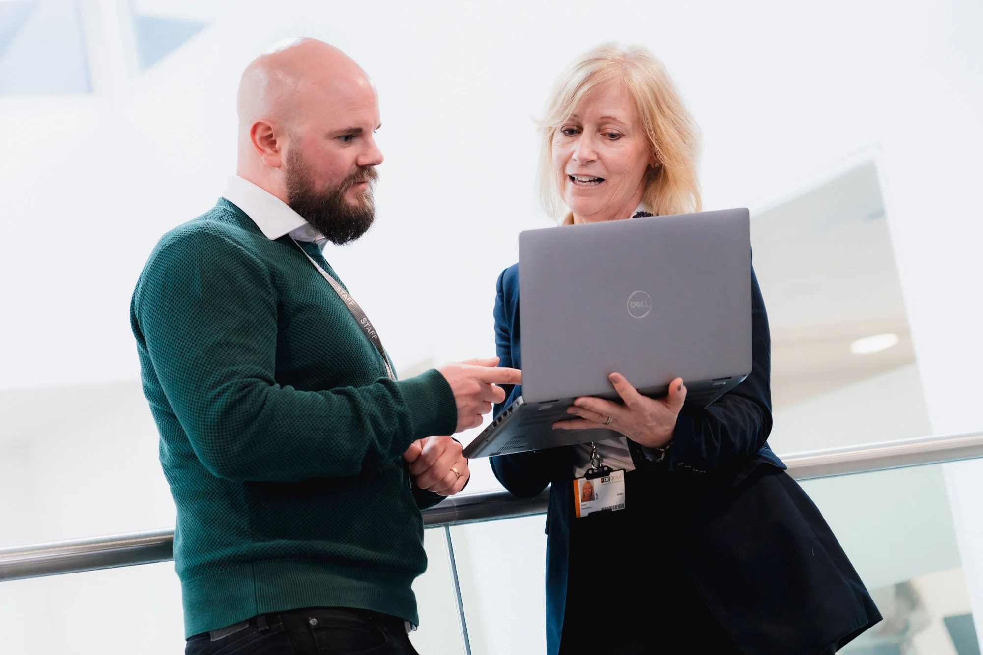 Two people standing looking at a laptop and chatting