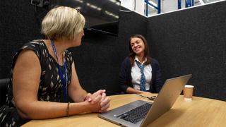 Total People colleague sits next to a smiling woman.