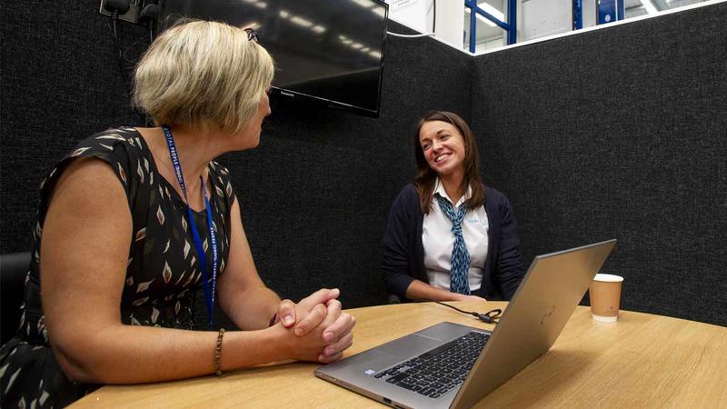 Total People colleague sits next to a smiling woman.