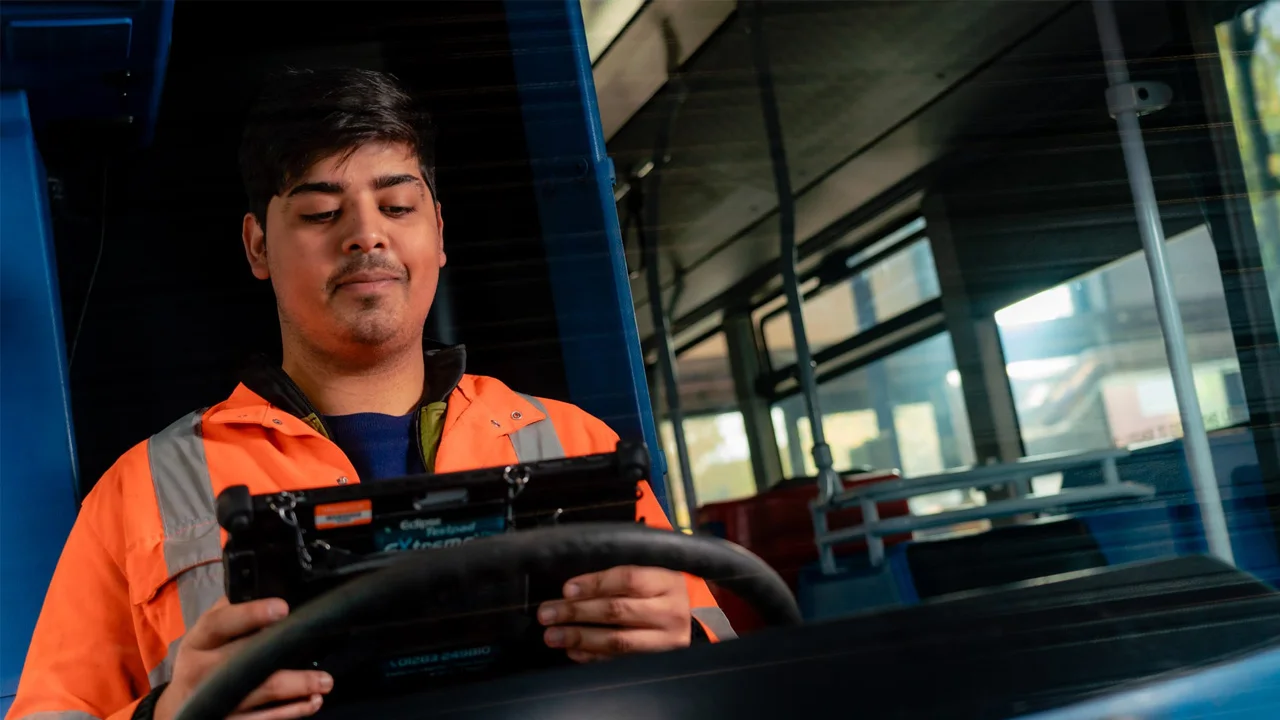 An engineer running diagnostics while sat behind the steering wheel of a coach