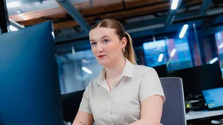 A Business Administration apprentice sits in front of her computer at her desk.