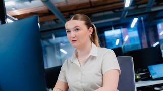 A Business Administration apprentice sits in front of her computer at her desk.