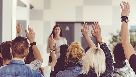 Students putting their hands up in a classroom