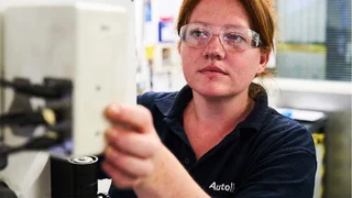 Female engineering apprentice using machinery.
