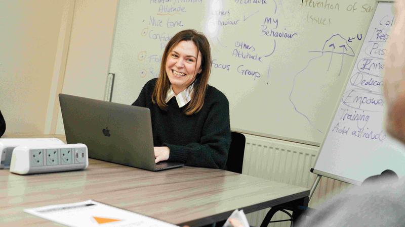 girl smiling at camera with a laptop