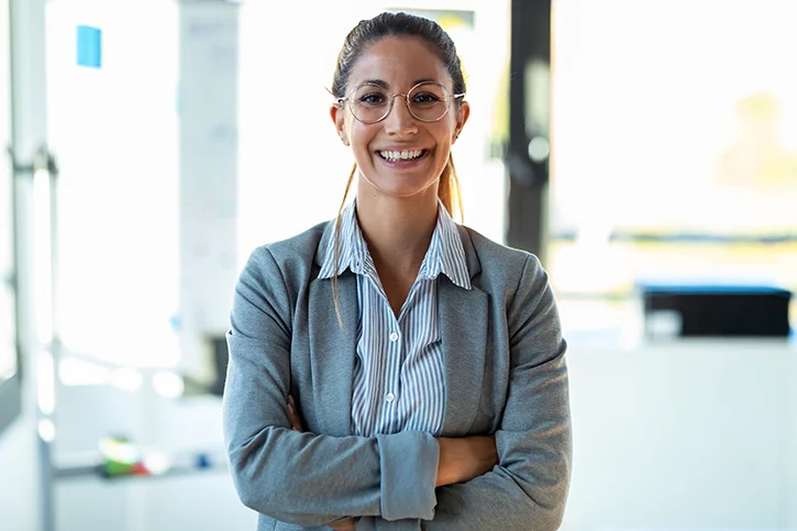 lady standing with her  arms folded smiling