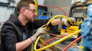 A refrigeration apprentice checks over his work
