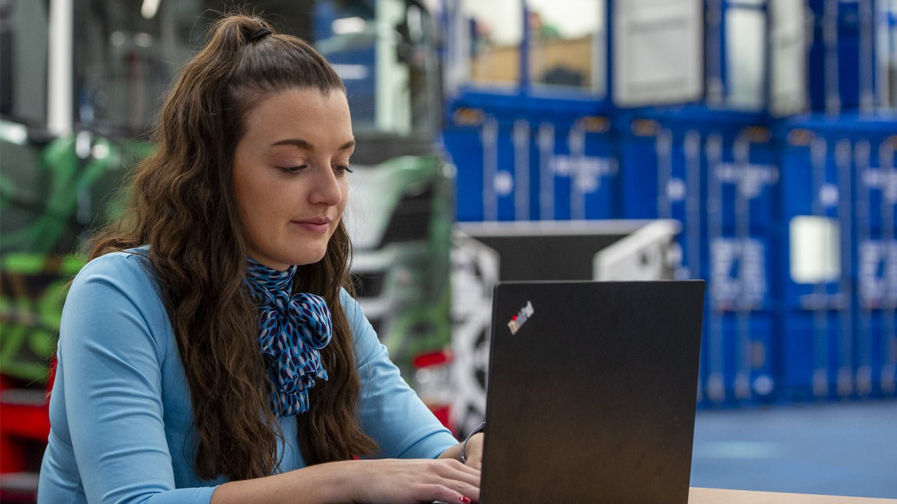 Female apprentice on laptop in front of HGV.