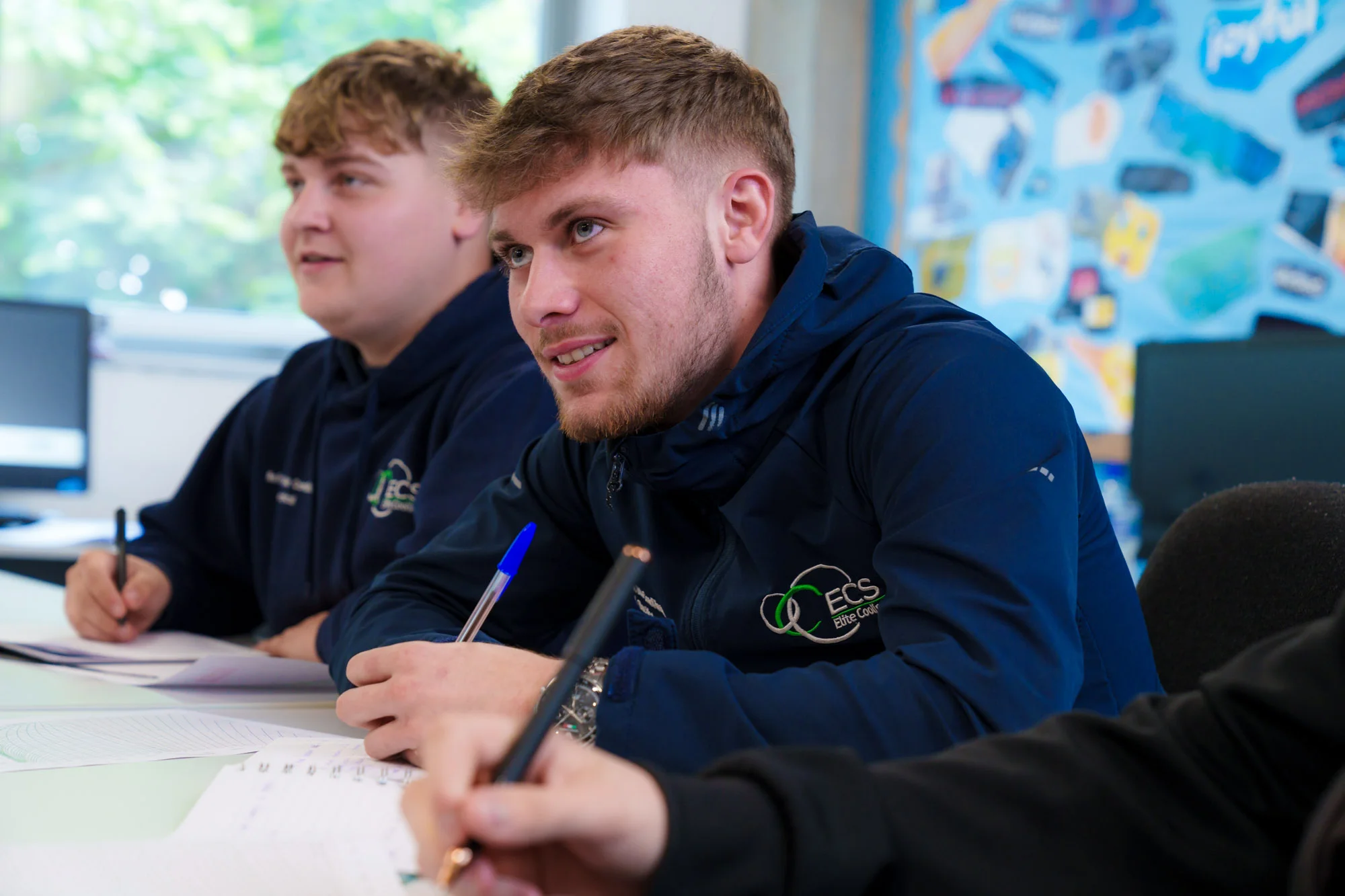 boy in a classroom holding a pen