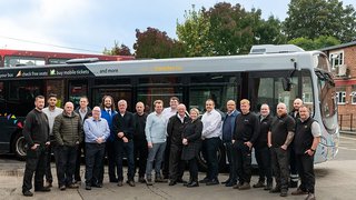 A group photo of the learners enrolled on the SkillUp programme, standing in front of a bus.