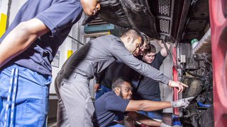 Metroline apprentices looking at a bus engine.