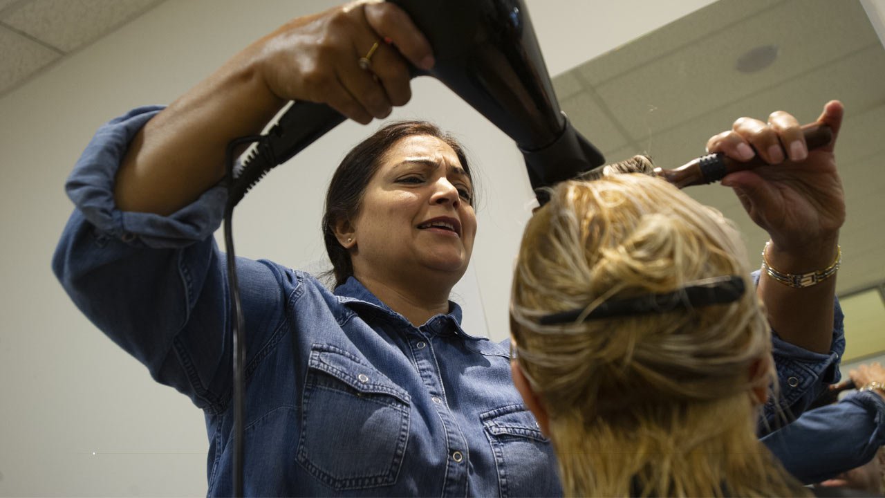 Hairstylist blow drying a client's hair.