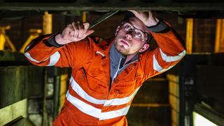 Male commercial vehicle apprentice repairing a bus.