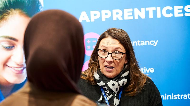 Apprenticeship advisor speaking to prospective learner at Total People apprenticeship information stand