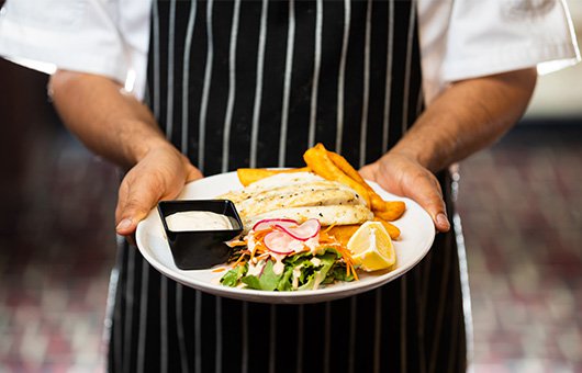 A chef holding a plate of freshly prepared food
