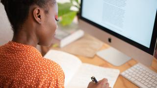 A woman sat at a desk writing in a notebook