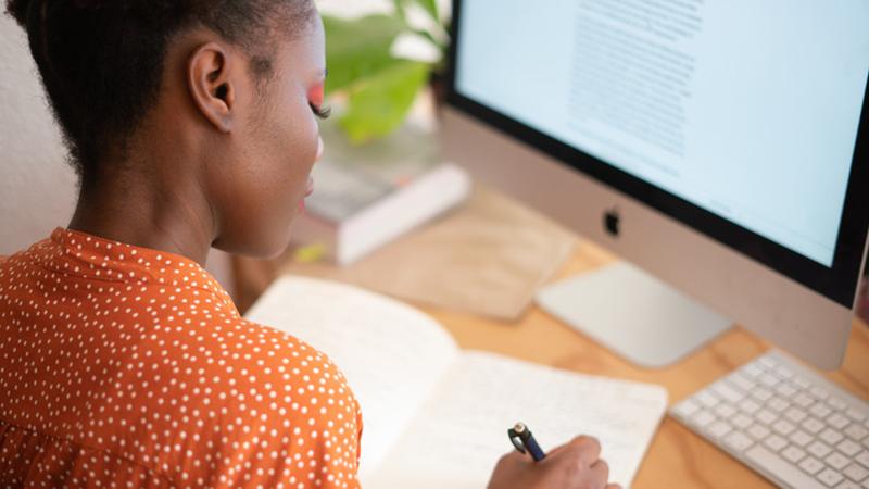 A woman sat at a desk writing in a notebook