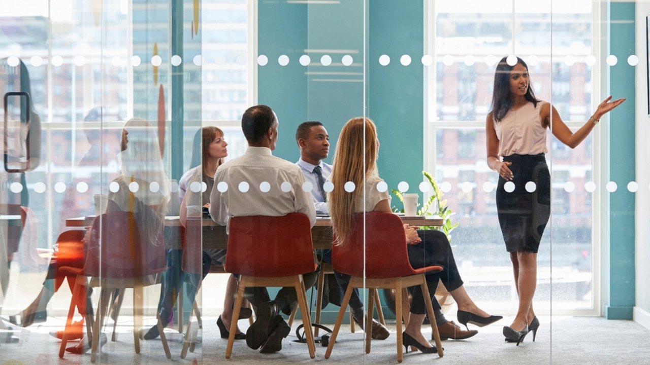 A group of people working in a glass meeting room