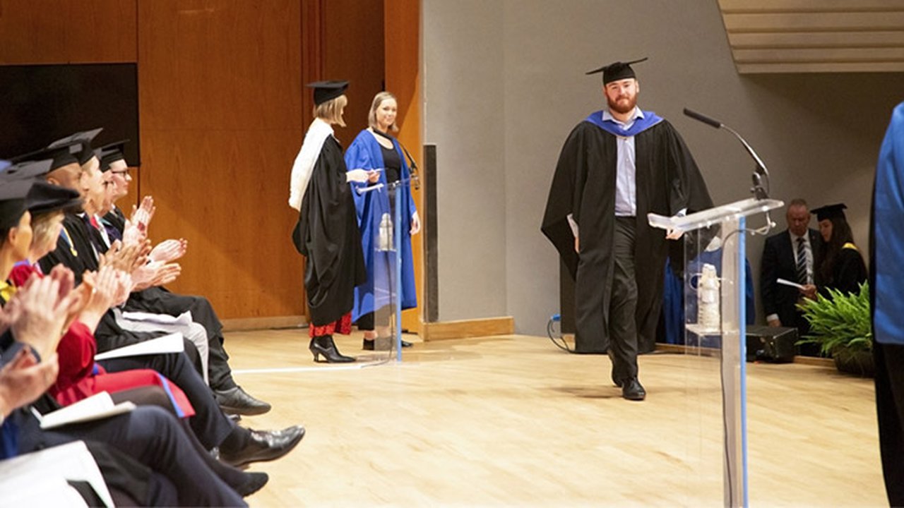 Graduate receiving his diploma on the Bridgewater Hall stage