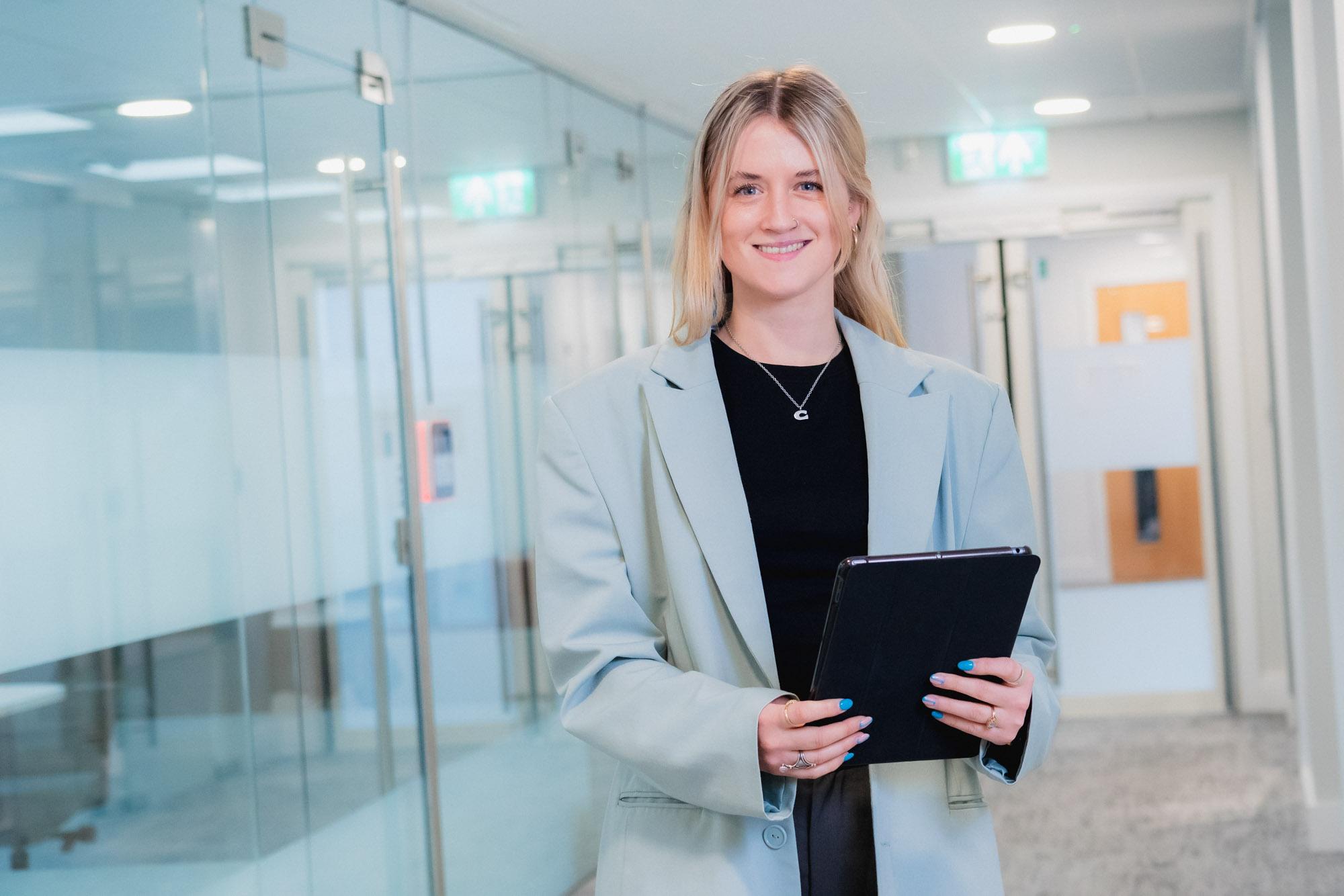 Lady standing with an ipad smiling